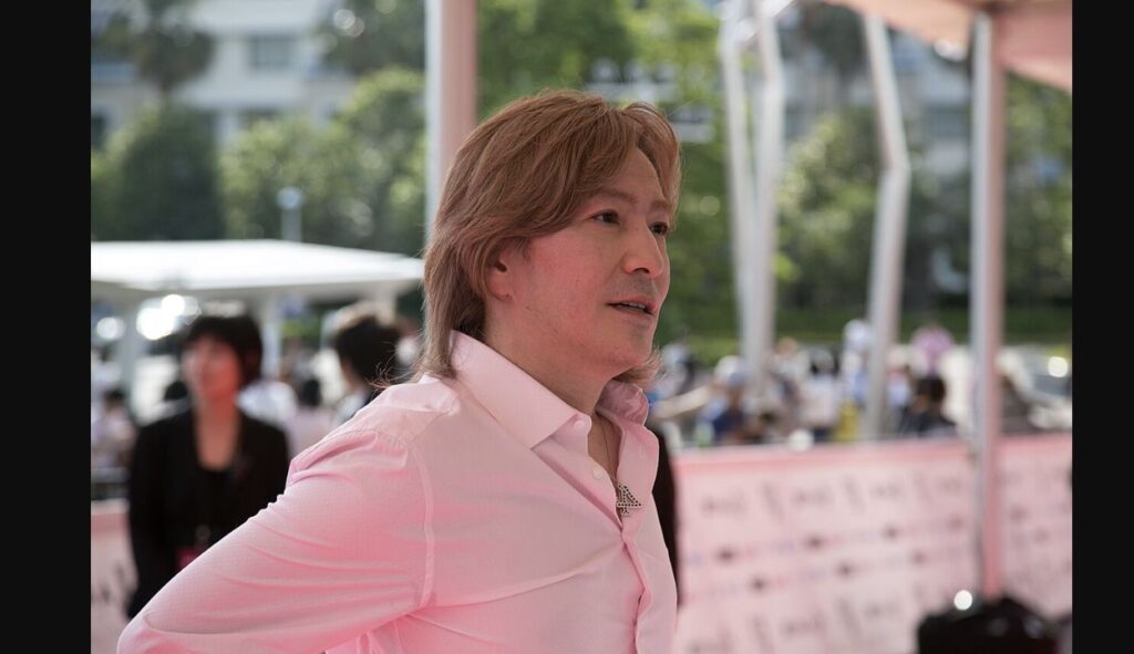 2014年のMTV VMAJ会場で、白いシャツを着て横を向く小室哲哉