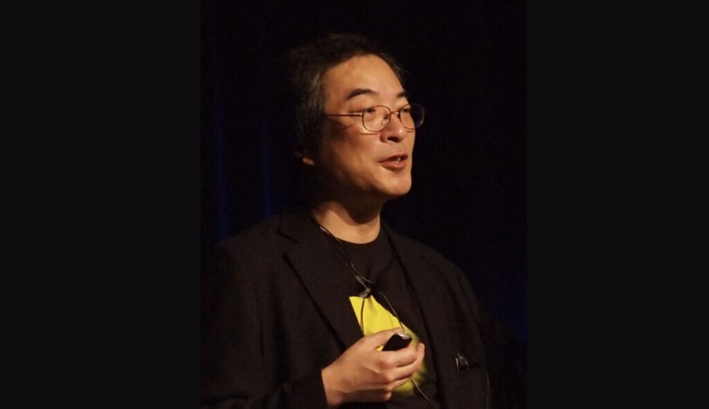 2011年のゲーム開発者会議GDCで講演する、眼鏡と黒いジャケット姿の岩谷徹